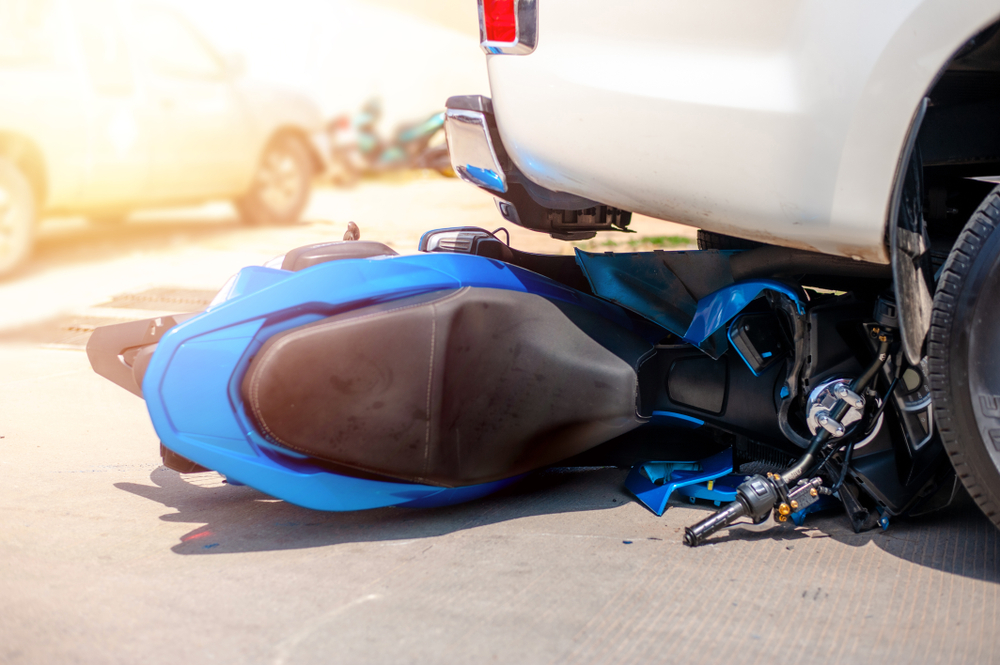Motorcycle down on the road next to a car after a highway collision